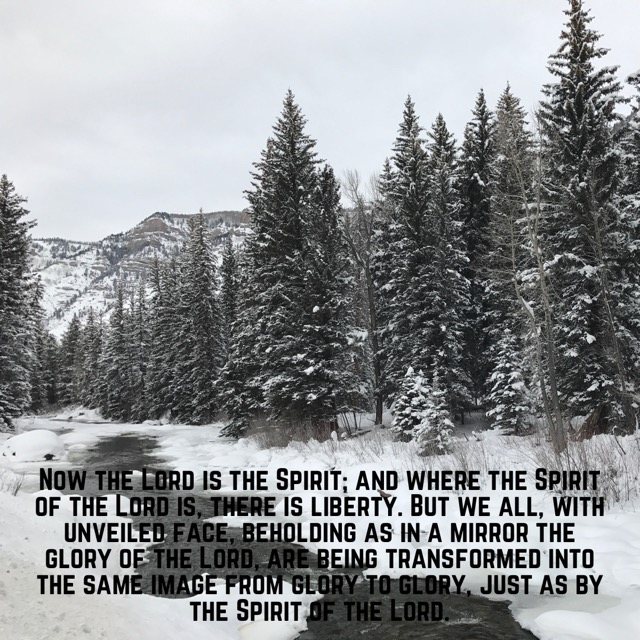 A snowy creek through evergreens, with the words of 2 Corinthians 3:17–18