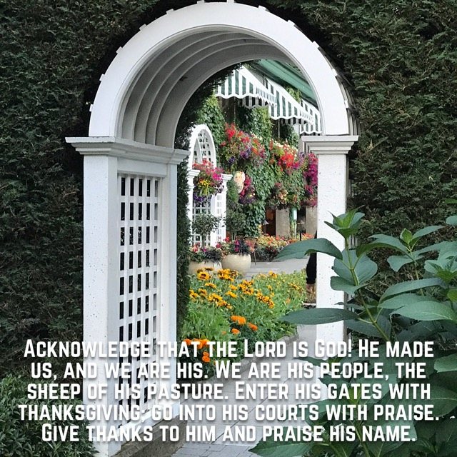 A white garden arch opening onto flowers, with the words of Psalm 100:3–4