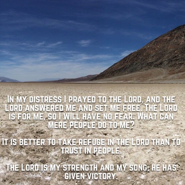 A wide salt flat beneath a dark mountain, with the words of Psalm 118:5–6, 8, 14