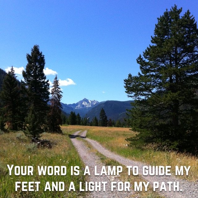 A dirt road through a meadow toward a peak, with the words of Psalm 119:105