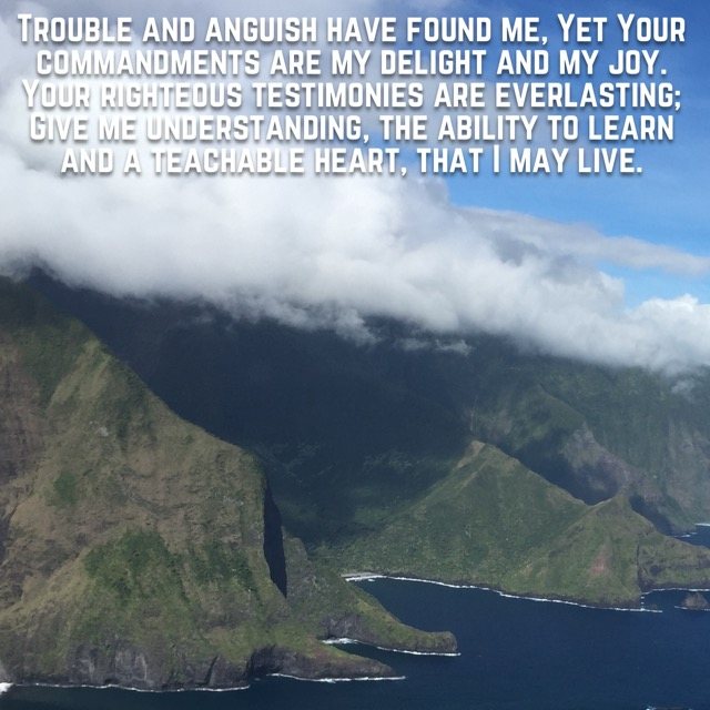 Clouds rolling over green sea cliffs, with the words of Psalm 119:143–144