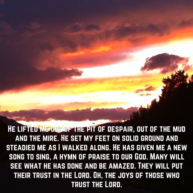 A blazing sunset over a mountain ridge, with the words of Psalm 40:2–4