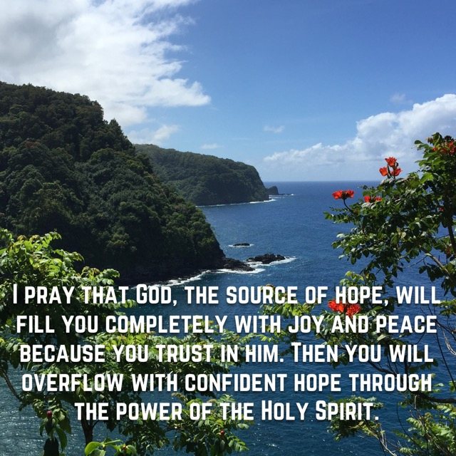 Green sea cliffs and red blossoms over blue ocean, with the words of Romans 15:13