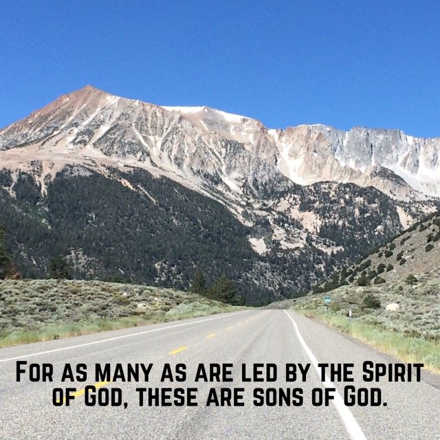 A highway leading toward a high mountain, with the words of Romans 8:14